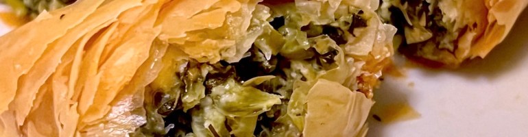 Piece of spanakopita broken open to show the filling.