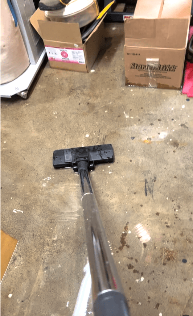 Image of a wet/dry shop vac sucking up water in a basement after a flood. 